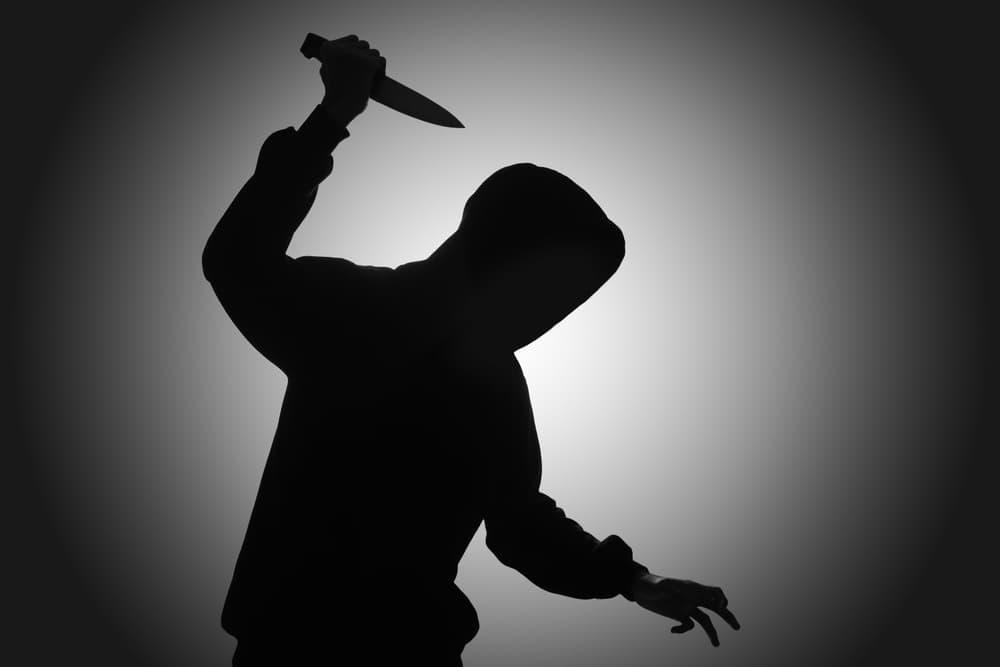 Mysterious man wearing black hoodie holding a knife to stab someone.